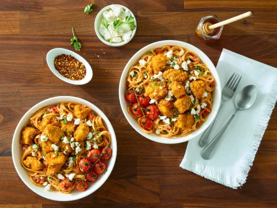 spicy honey chicken breast chunks dance with creamy tomato sauce and tangy feta on a stage of tender linguine