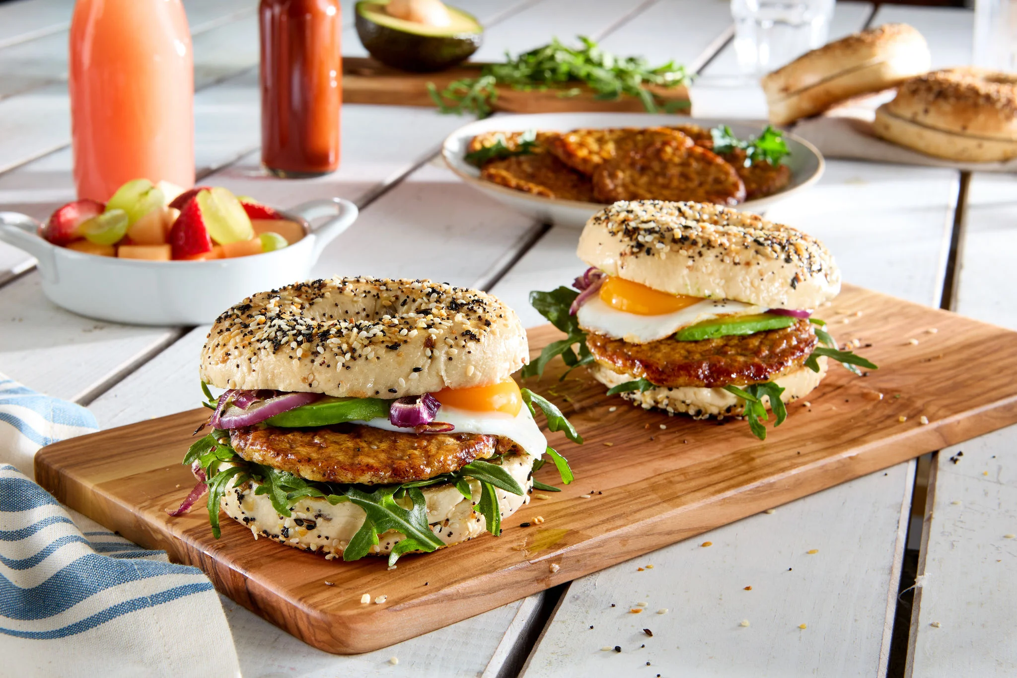 Bagel sandwich with chicken sausage, cheese, avocado, red onion, egg, and arugula