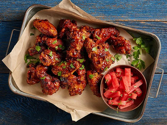 BBQ bone in chicken wings with pickled watermelon on a platter