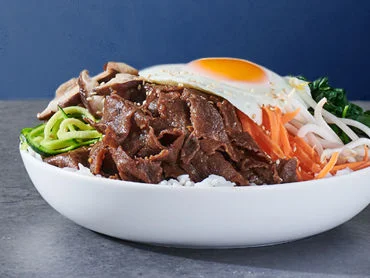 Bibimbap breakfast bowl with a variety of fresh sautéed vegetables, jasmine rice, bibimbap sauce, and a sunny side egg