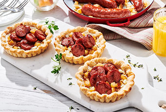 Three tart pies with sausages on a white cutting board