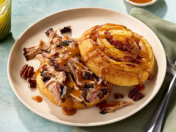 Pulled pork between layers of sticky bun topped with pecans and caramel swirl