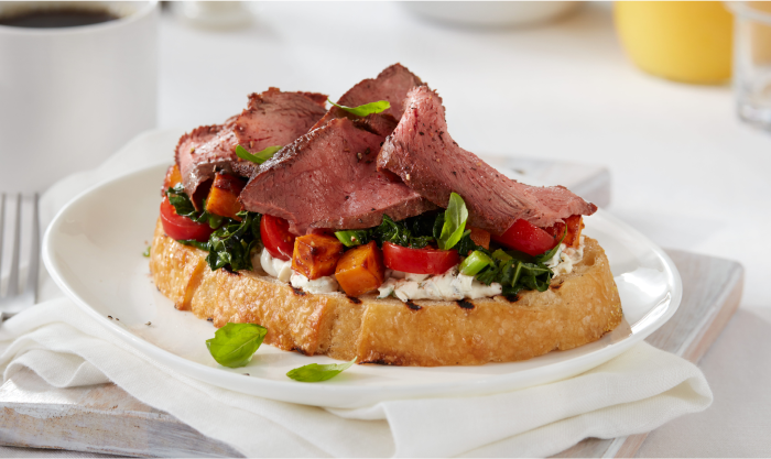 Bread topped with vegetables and sliced steak